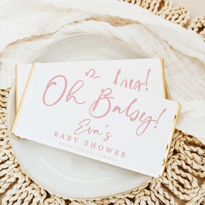 Pode incluir: Um cartão branco com acabamento dourado e texto rosa que diz "Oh Baby! Eva's Baby Shower Thank You for Coming!"