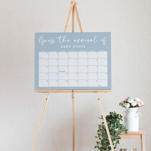 May include: A blue calendar with the text "Guess the arrival of Baby Davis" on a wooden easel. The calendar has the months of August, September, October, November, and December. The due date is marked on the calendar.