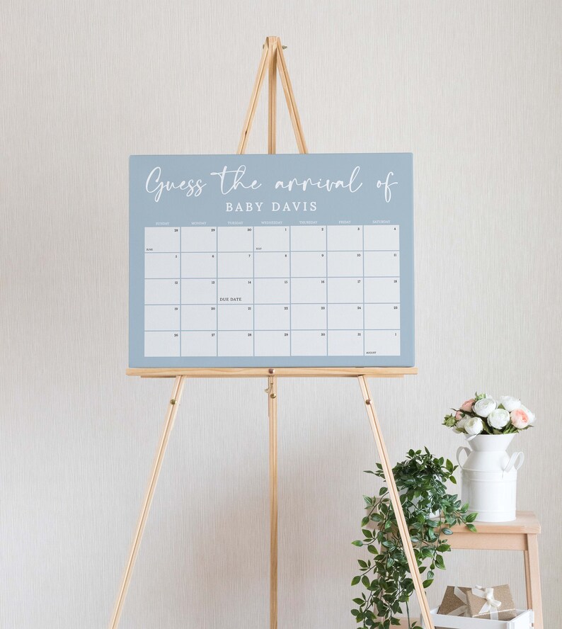 May include: A blue calendar with the text "Guess the arrival of Baby Davis" on a wooden easel. The calendar has the months of August, September, October, November, and December. The due date is marked on the calendar.