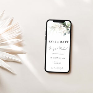 Puede incluir: La pantalla de un tel&eacute;fono m&oacute;vil que muestra un anuncio de guardar la fecha para una boda. El anuncio presenta una ilustraci&oacute;n de acuarela de hojas verdes y acentos dorados. El texto dice "Save the Date" con los nombres de la pareja "Jennifer & Michael" y la fecha de la boda "18 | MAYO | 2024".
