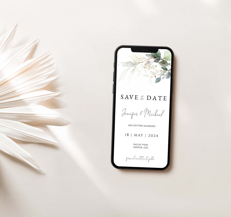 Puede incluir: La pantalla de un tel&eacute;fono m&oacute;vil que muestra un anuncio de guardar la fecha para una boda. El anuncio presenta una ilustraci&oacute;n de acuarela de hojas verdes y acentos dorados. El texto dice "Save the Date" con los nombres de la pareja "Jennifer & Michael" y la fecha de la boda "18 | MAYO | 2024".