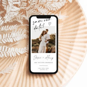 May include: A save the date card with a photo of a couple in a field. The text reads "Save our date!" with a small heart icon. Below the photo, it says "Josie + Harry are getting married!" and the date and location: "July 8th, 20XX, Austin, TX".