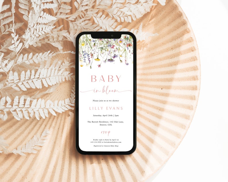 May include: A digital invitation for a baby shower with a floral design. The invitation reads "Baby in Bloom" and includes the name "Lilly Evans" and the date and time of the event. RSVP information is also included.