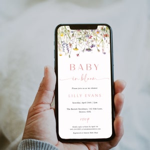 May include: A baby shower invitation on a smartphone screen with a floral design. The invitation reads "Baby in Bloom" and includes the name "Lilly Evans", the date and time of the shower, the location, and RSVP information.