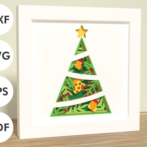 May include: A white frame with a green, yellow, and red paper cut-out Christmas tree design. The tree has a yellow star on top and is decorated with red berries and yellow ornaments.