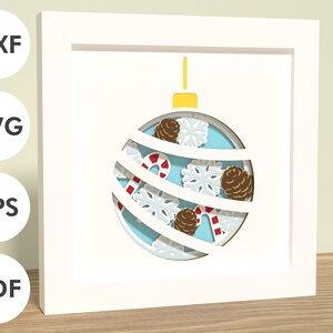 May include: A white frame with a blue and white paper ornament inside. The ornament is decorated with snowflakes, pine cones, and candy canes.