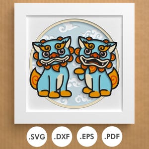 May include: A digital paper craft design featuring two blue lion-like creatures with orange accents and a white background with blue clouds. The design is in a circle with a white frame.