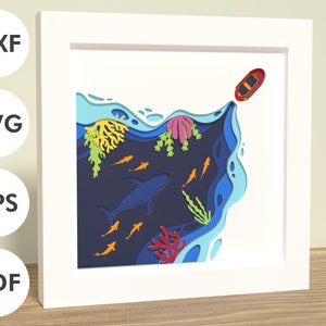 May include: A paper cut-out design of a red boat sailing over a blue ocean with coral reefs, fish, and a shark. The design is layered and intricate, creating a 3D effect.
