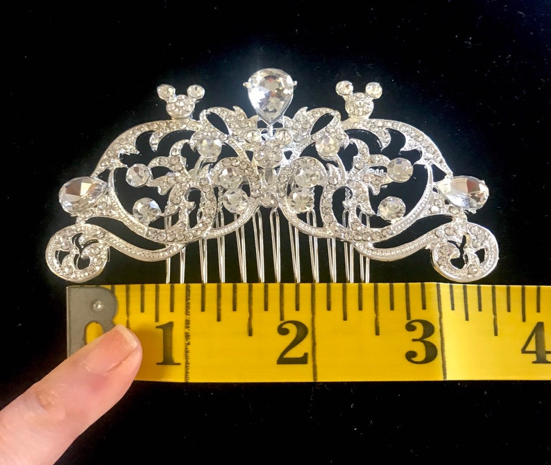 K&ouml;nnte beinhalten: Silberner Haarkamm mit Strassstein-Design und zwei Mickey-Maus-Ohren. Der Kamm ist etwa 7,6 cm lang.