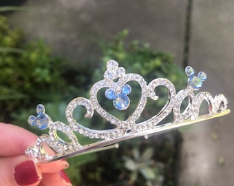 May include: Silver tiara with blue rhinestone Mickey Mouse ears and clear rhinestones.