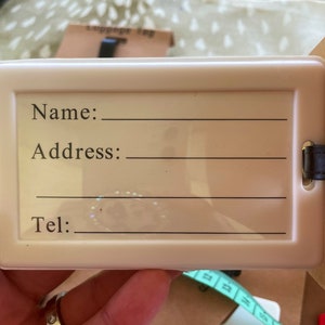 K&ouml;nnte beinhalten: Wei&szlig;er Gep&auml;ckanh&auml;nger mit schwarzem Text, der "Name:", "Adresse:" und "Tel:" lautet, mit leeren Zeilen zum Ausf&uuml;llen der Informationen.