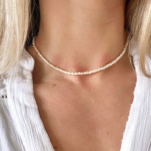 May include: A delicate white beaded choker necklace. The necklace is made of small, round beads that are strung together on a thin chain. The necklace is simple and elegant, and would be a great addition to any jewellery collection.
