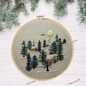 Embroidery kit featuring 3 cabins nestled in a-snowy pine woods