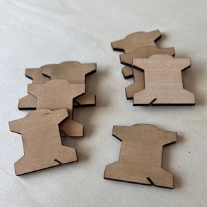 May include: A set of ten unfinished wooden thread spools. The spools are light brown and have a black outline. They are arranged in three groups on a white surface.