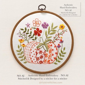 May include: Hand-stitched embroidery art featuring a pumpkin with floral accents in a wooden hoop. The pumpkin is orange and white with a variety of floral designs. The text reads "Authentic Hand Embroidery NO AI".