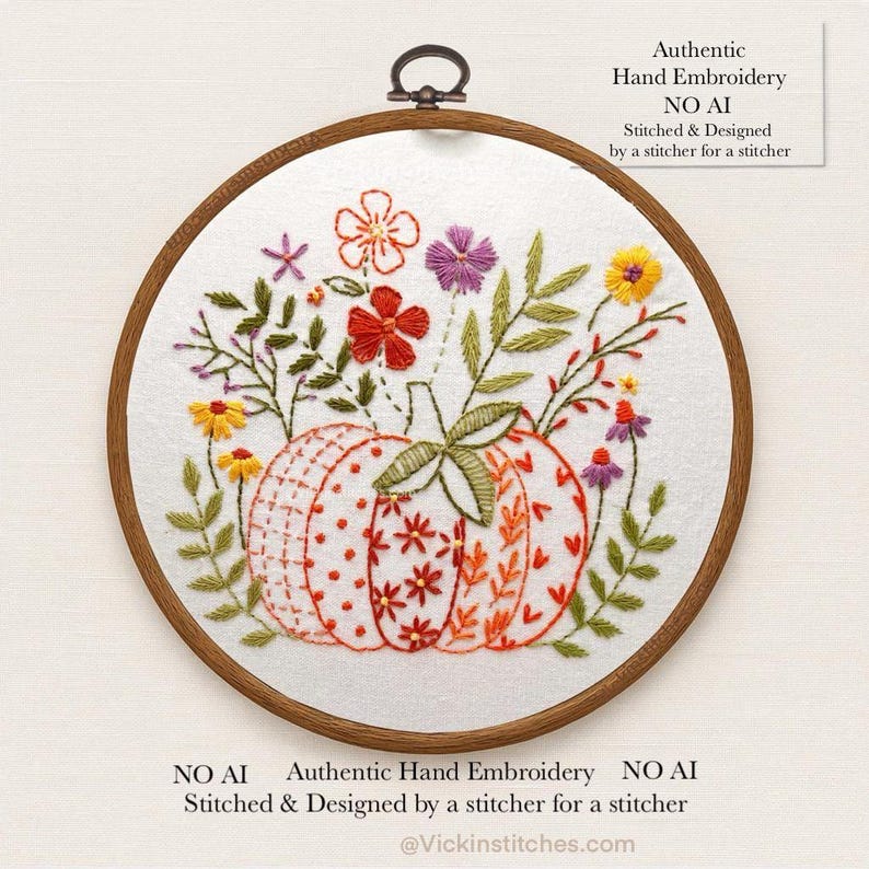 May include: Hand-stitched embroidery art featuring a pumpkin with floral accents in a wooden hoop. The pumpkin is orange and white with a variety of floral designs. The text reads "Authentic Hand Embroidery NO AI".