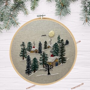 Embroidery kit featuring 3 cabins nestled in a-snowy pine woods