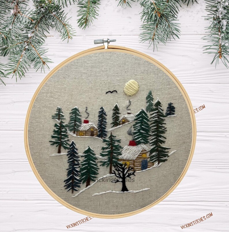 Embroidery kit featuring 3 cabins nestled in a-snowy pine woods