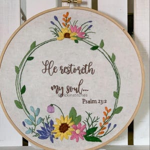 May include: Embroidered hoop art featuring a floral wreath and the text "He restoreth my soul... Psalm 23:2".