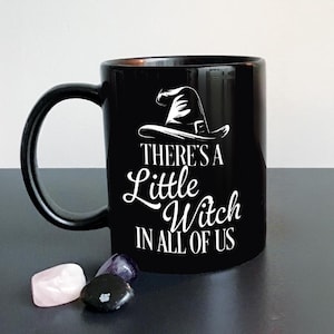 May include: Black coffee mug with a white witch hat and the text "There's a Little Witch in All of Us".
