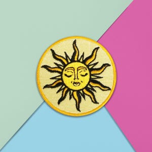 May include: Embroidered patch depicting a smiling sun with closed eyes. The sun has yellow rays and a yellow face with black details, set against a light yellow circular background. Suitable for clothing or accessories.