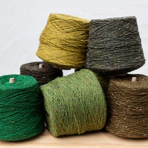 Peut inclure: Six bobines de fil de différentes nuances de vert, marron et jaune. Le fil est enroulé serré et a une apparence texturée.