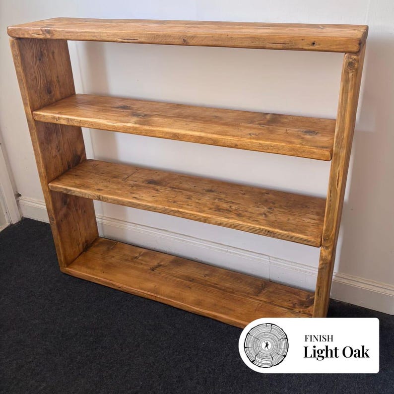May include: A rectangular wooden shelving unit with a light oak finish, featuring four horizontal tiers including the top and bottom surfaces. The wood grain is visible throughout the structure, which has a simple, open-frame design.