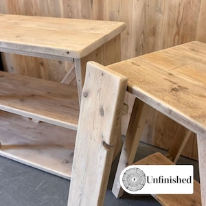 May include: Two unfinished wooden tables with a natural, light-coloured finish. The tables have a rustic design, with visible wood grain and a sturdy build. One table has a lower shelf. The text "Unfinished" is visible on the bottom right.