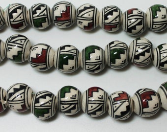 Perles rondes péruviennes de 12x10 mm avec motifs géométriques rouges et verts, vendues par le brin de 10 pièces