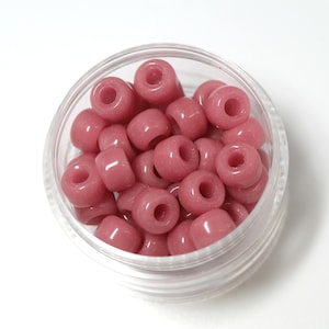 May include: A clear plastic container filled with approximately 30 pink round beads. The beads have a slightly matte finish.