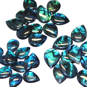 May include: A collection of iridescent abalone shell teardrop-shaped cabochons in shades of blue and green. The cabochons are arranged in three groups on a white background.