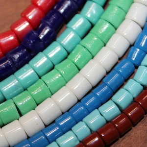 May include: A close-up of a colorful beaded necklace with red, blue, green, white, and turquoise beads. The beads are cylindrical and have a glossy finish.