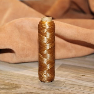 May include: A spool of golden brown waxed thread for leather crafting.