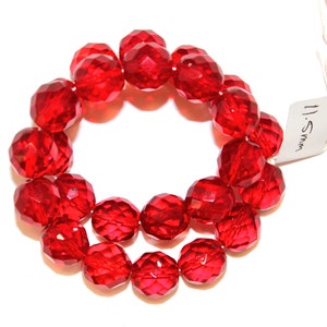 May include: A strand of 11mm red faceted glass beads. The beads are round and have a shiny finish.