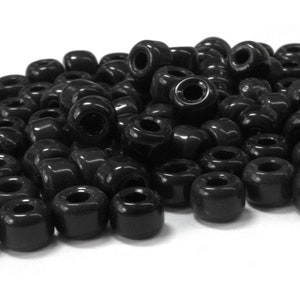 May include: A large pile of black plastic round beads. The beads have a hole in the center.