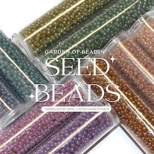May include: Assortment of seed beads in various colors, including green, brown, purple, and gold. The beads are in small glass tubes with the text "GARDEN OF BEADIN' SEED BEADS TRANSLUCENT OPAL LUSTER VARIETY PACK" on the label.