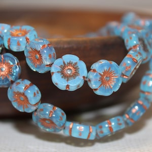 May include: A strand of blue glass beads with copper accents, each bead is shaped like a flower with a raised center.
