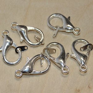 May include: Six silver-toned lobster clasps, a type of fastener used in jewelry making.