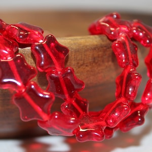May include: A strand of red glass star-shaped beads. The beads are translucent and have a shiny finish.
