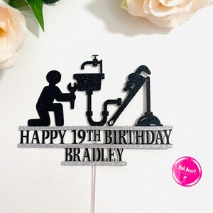 May include: Black and silver cake topper with a plumber silhouette, a sink, a wrench, and the text "Happy 19th Birthday Bradley".