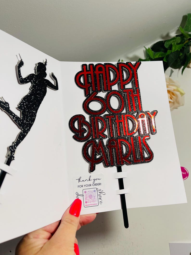 May include: Red and silver glitter cake topper with the text "Happy 60th Birthday Maris".