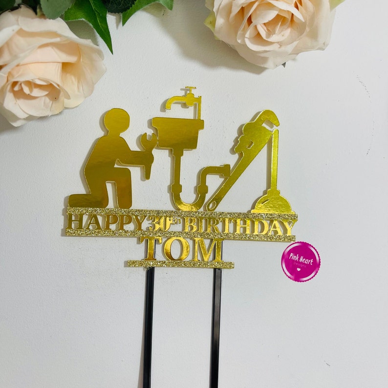 May include: Gold glitter cake topper featuring a plumber silhouette with a wrench, pipes, and a sink. The topper says "Happy 30th Birthday Tom".