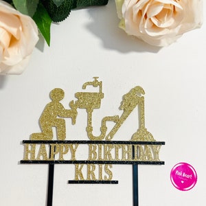 May include: Gold glitter cake topper with a plumber silhouette, pipes, and a sink. The topper says "Happy Birthday Kris" on two black banners.