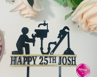 May include: Black cake topper featuring a silhouette of a plumber holding a wrench and a pipe. The topper reads "Happy 25th Josh" in gold glitter.