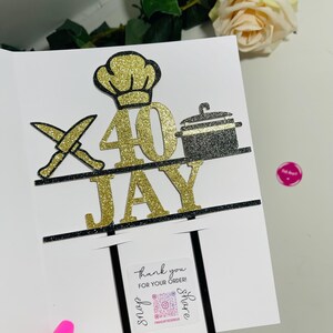 May include: A white card with a gold glitter "40" and "JAY" cake topper. The topper features a chef's hat, crossed knives, and a pot. A small sticker reads "thank you for your order!" with social media details.