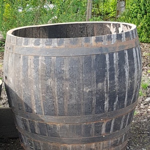 May include: A large, weathered wooden barrel with metal bands. The barrel is dark brown and has a rustic appearance.