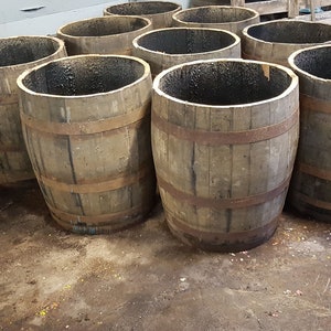 May include: A collection of wooden barrels with metal bands, used for storage or decoration. The barrels are empty and have a rustic, weathered look.