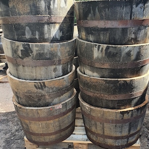 May include: A stack of six wooden barrels, each with a dark brown stain and a metal band around the top. The barrels are stacked in a pyramid shape, with the largest barrel at the bottom and the smallest barrel at the top.