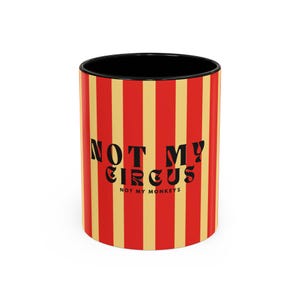 Puede incluir: Una taza de cerámica a rayas rojas y amarillas con texto negro que dice "Not My Circus, Not My Monkeys".
