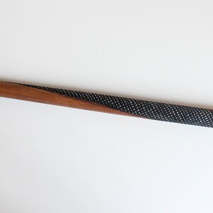 May include: A wooden walking stick with a carved green lizard handle. The stick is brown with a black and white patterned section.